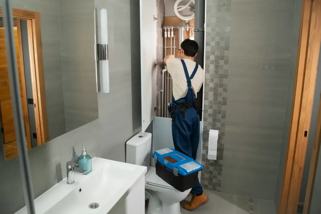 Plumber repairing concealed bathroom pipework