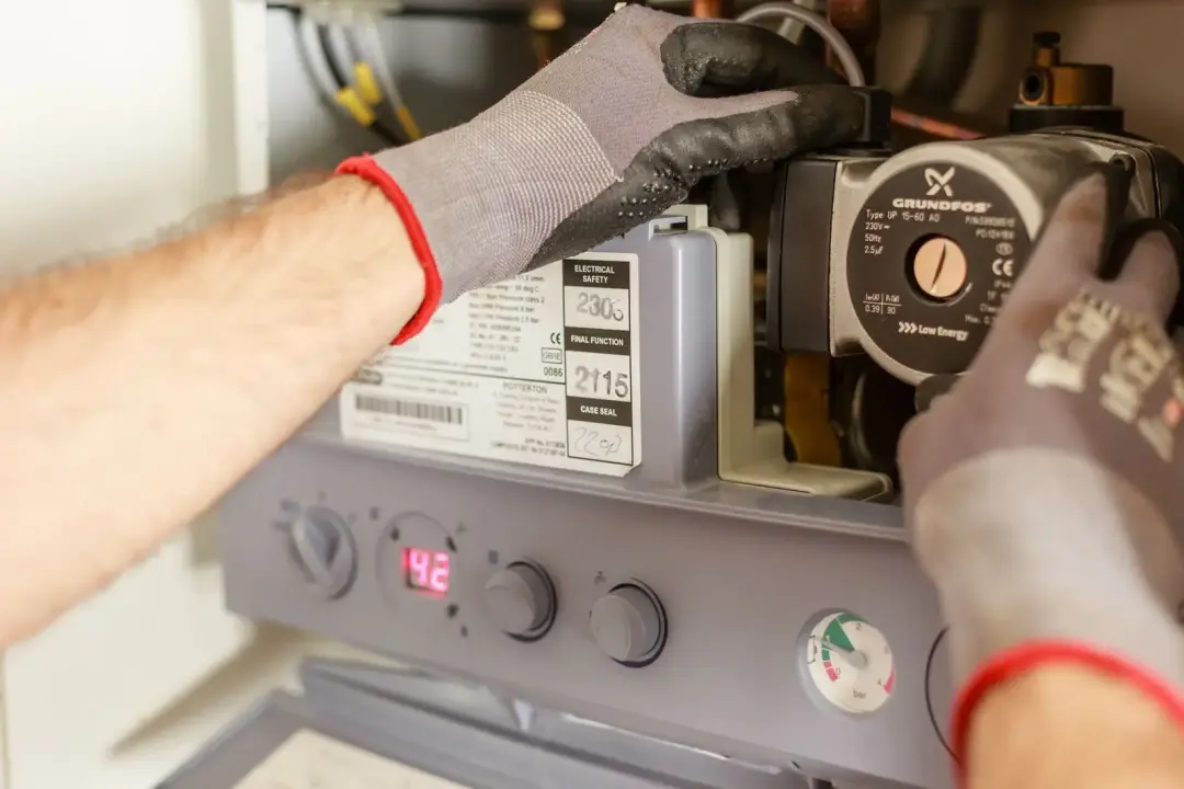 Hands inspecting the controls of a boiler system